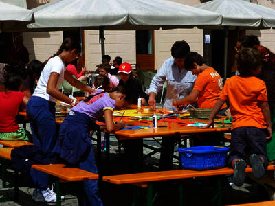 Febbrile attività di ragazze e ragazzi ai tavoli della fabbrica degli smilzi